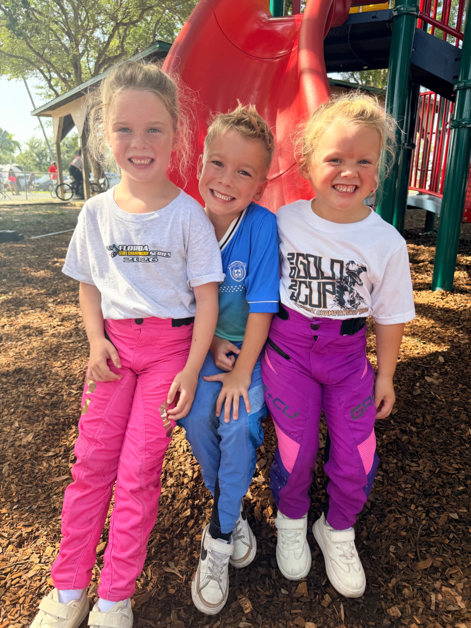 Sage, Sullivan, and Summer Cagle smiling together after racing