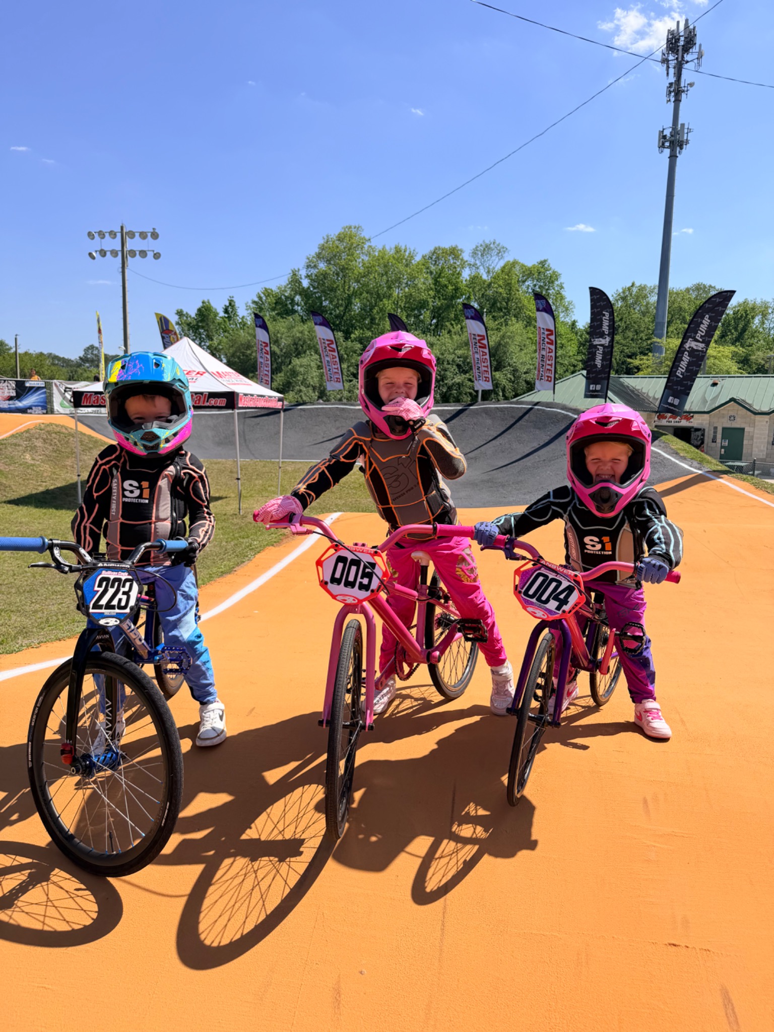 Sullivan, Sage, and Summer Cagle together with their BMX bikes at the track